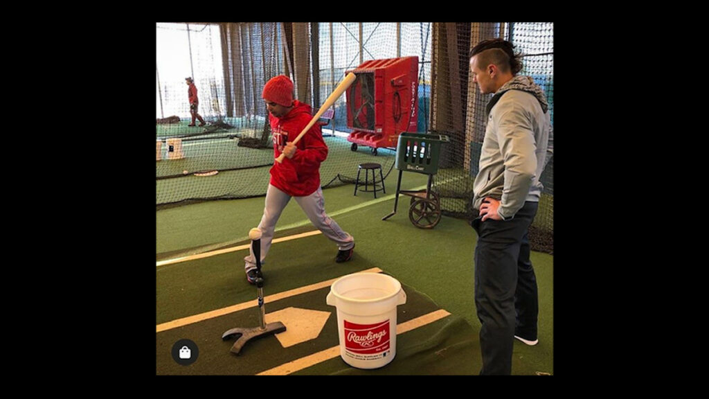 coach and player in a batting cage